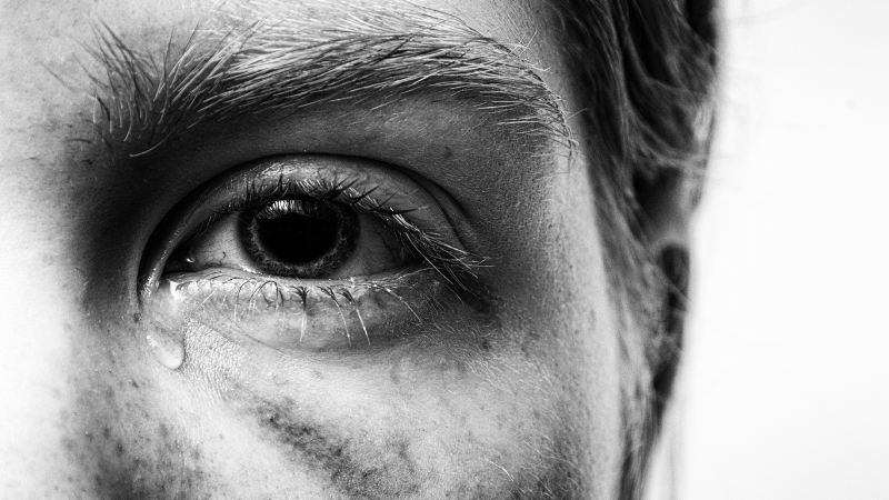 Black and white image of a man's eye with a tear, representing generational trauma in North Port.